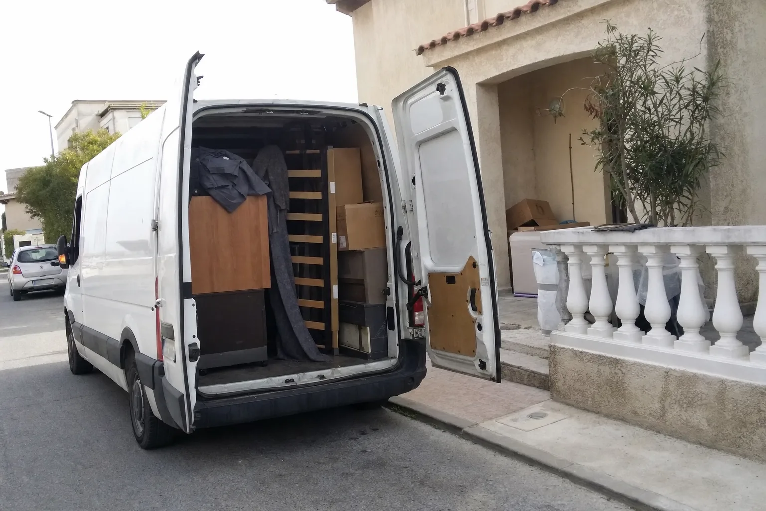 Fourgon chargé de cartons et de meubles devant une maison