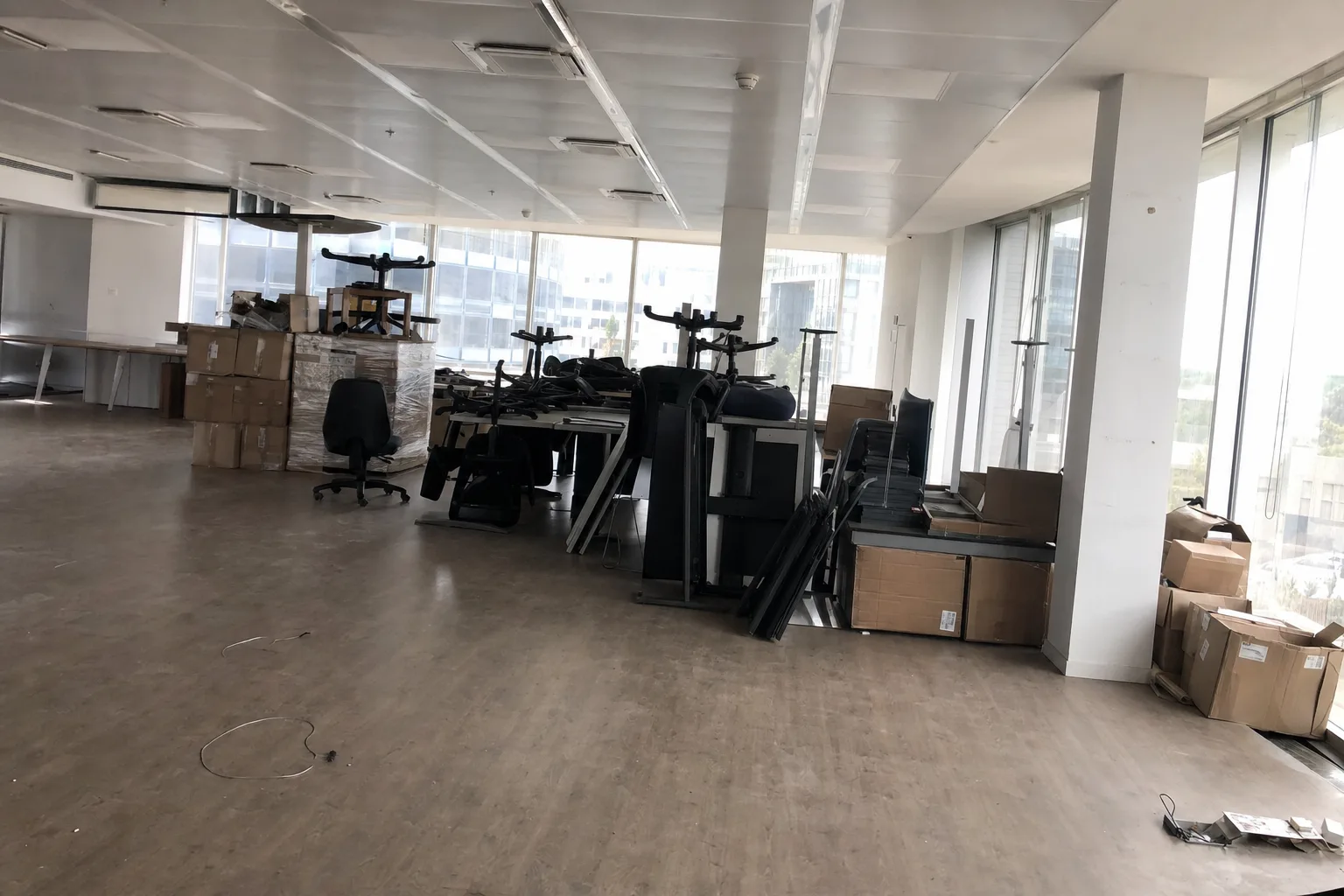 Open space de bureaux en cours de débarras, mobilier empilé et cartons