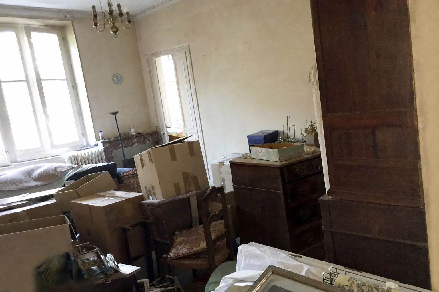 Salon d'une maison familiale en cours de débarras, cartons et meubles anciens