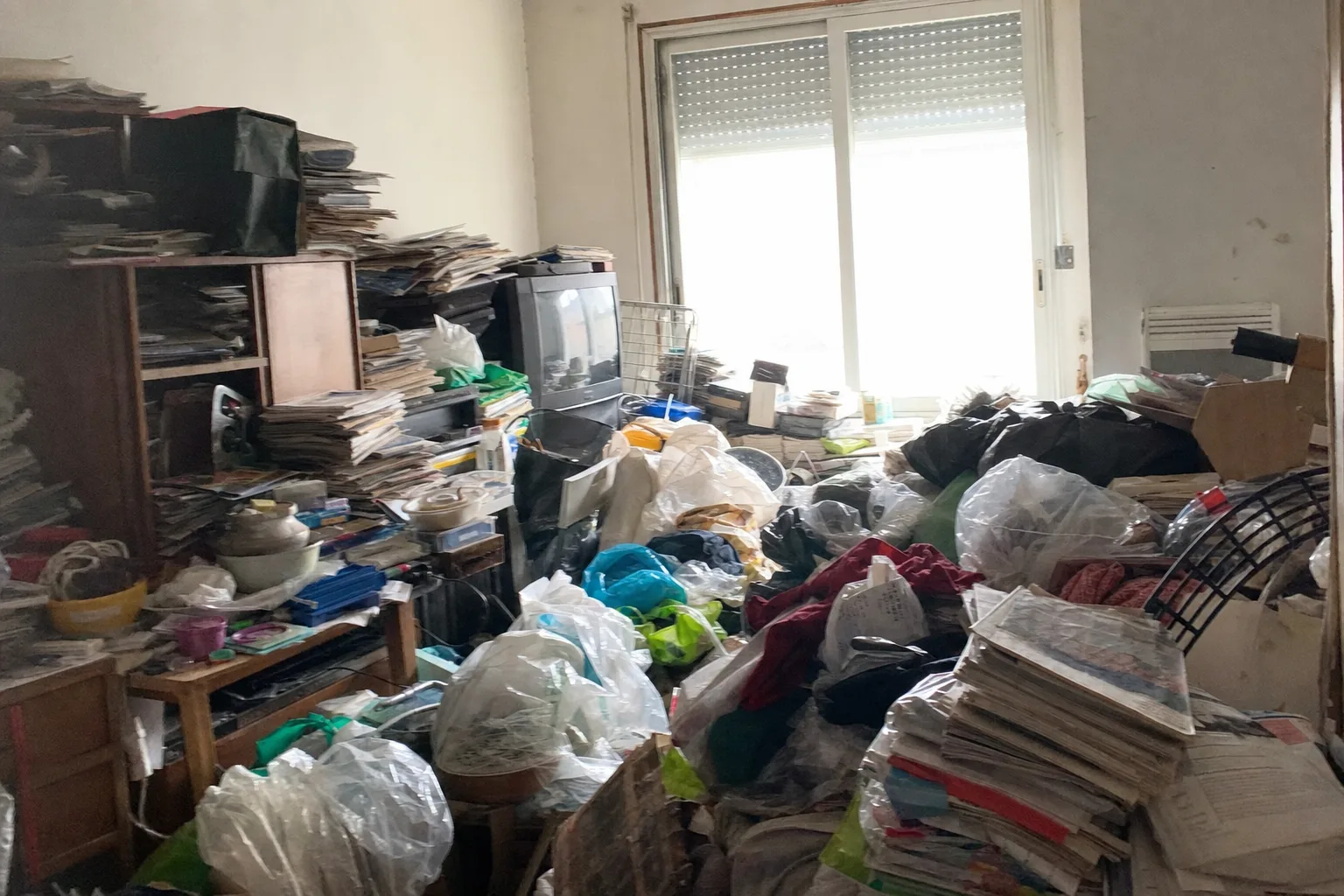 Pièce d'appartement très encombrée d'objets et de piles de papiers